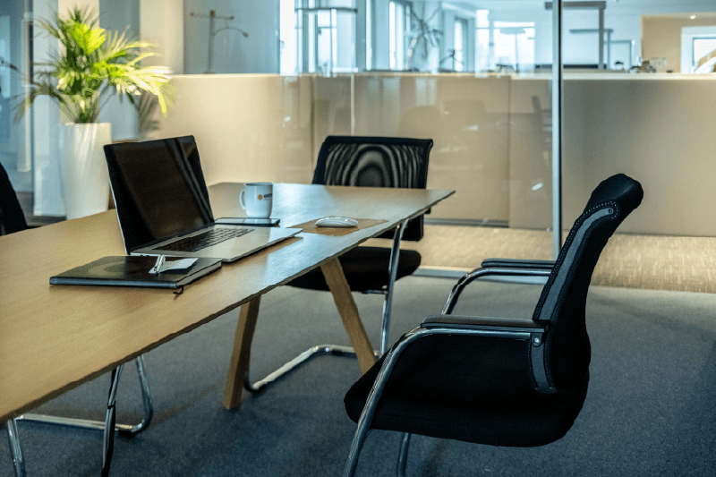 Besprechungstisch mit Laptop und Konferenzstühlen